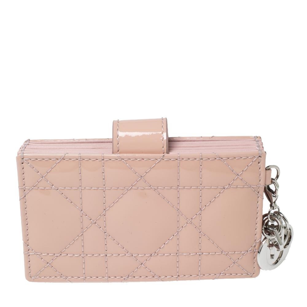 An emblematic creation from the House of Dior, this Lady Dior card holder exemplifies charm and luxury in every way. This card holder is created using powder-pink Cannage patent leather on the exterior and is installed with multiple gussets. It is