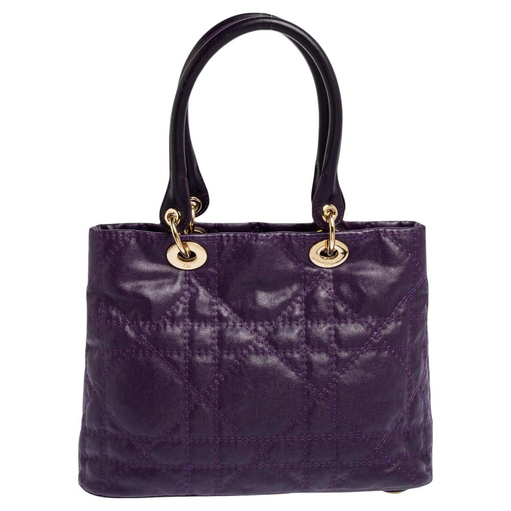 This Lady Dior tote comes made from purple-coated canvas and features the signature cannage quilt on the exterior. It has dual top handles carrying attached 'DIOR' letter charms and a nylon-lined interior that offers a lot of space to easily carry