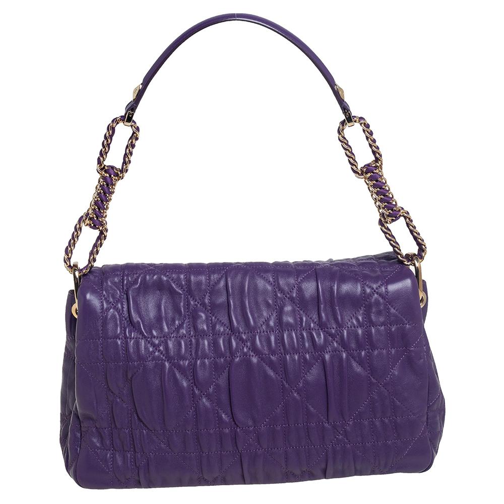 Fall in love almost instantly with this lovely bag from Dior. It is crafted from purple leather and features the brand's signature cannage pattern on the exterior. It has a front flap that opens to a spacious canvas interior and is held by a woven