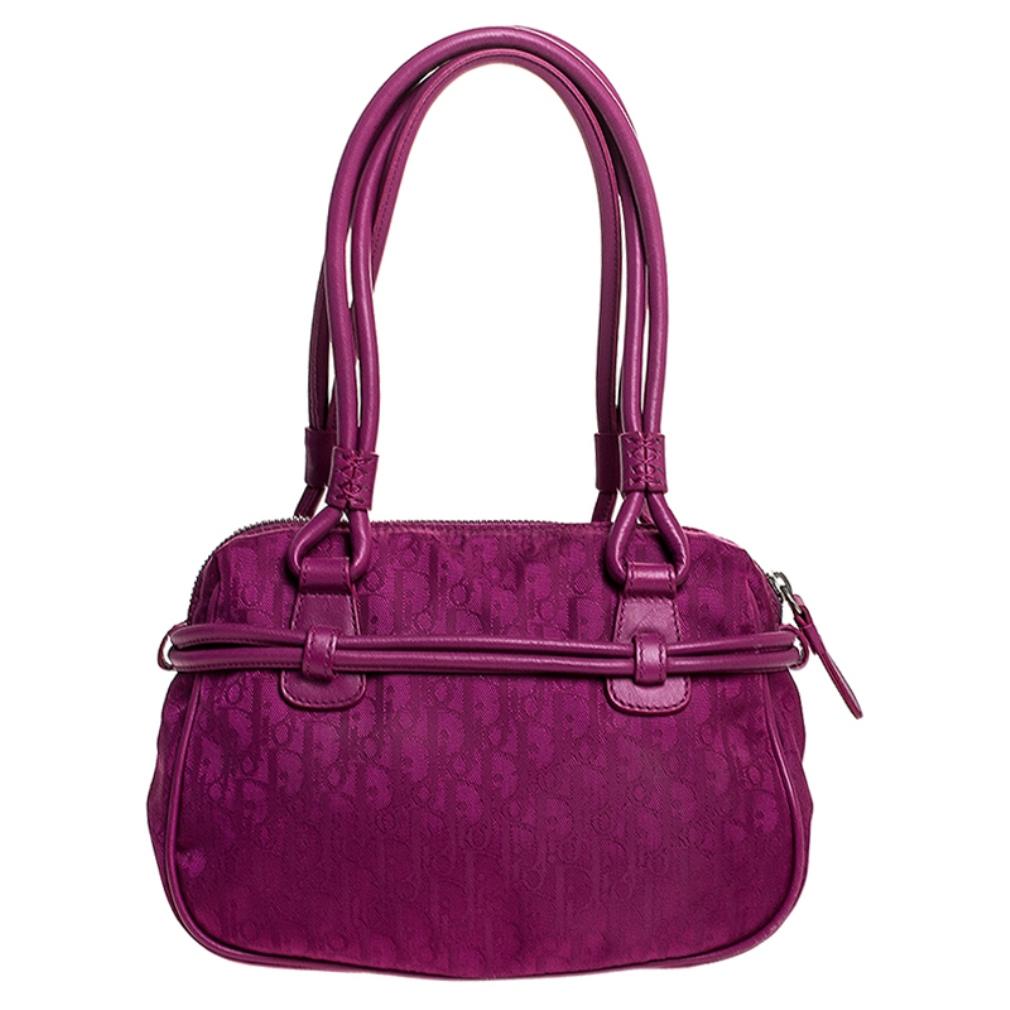 This Dior handbag promises to take you from day to night and weekday to weekend. It is crafted from nylon and leather and showcases the brand's signature monogram throughout. The exterior is beautified with a bow detailing with the ends features the
