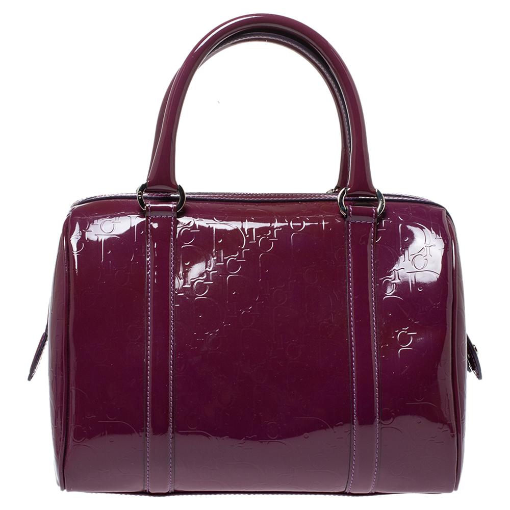 This Boston bag by Dior sweetly embodies luxe elegance! Crafted from monogram patent leather, this pretty bag features a top zip closure that opens to a canvas interior housing the brand label and a zip pocket. It is completed with twin handles and