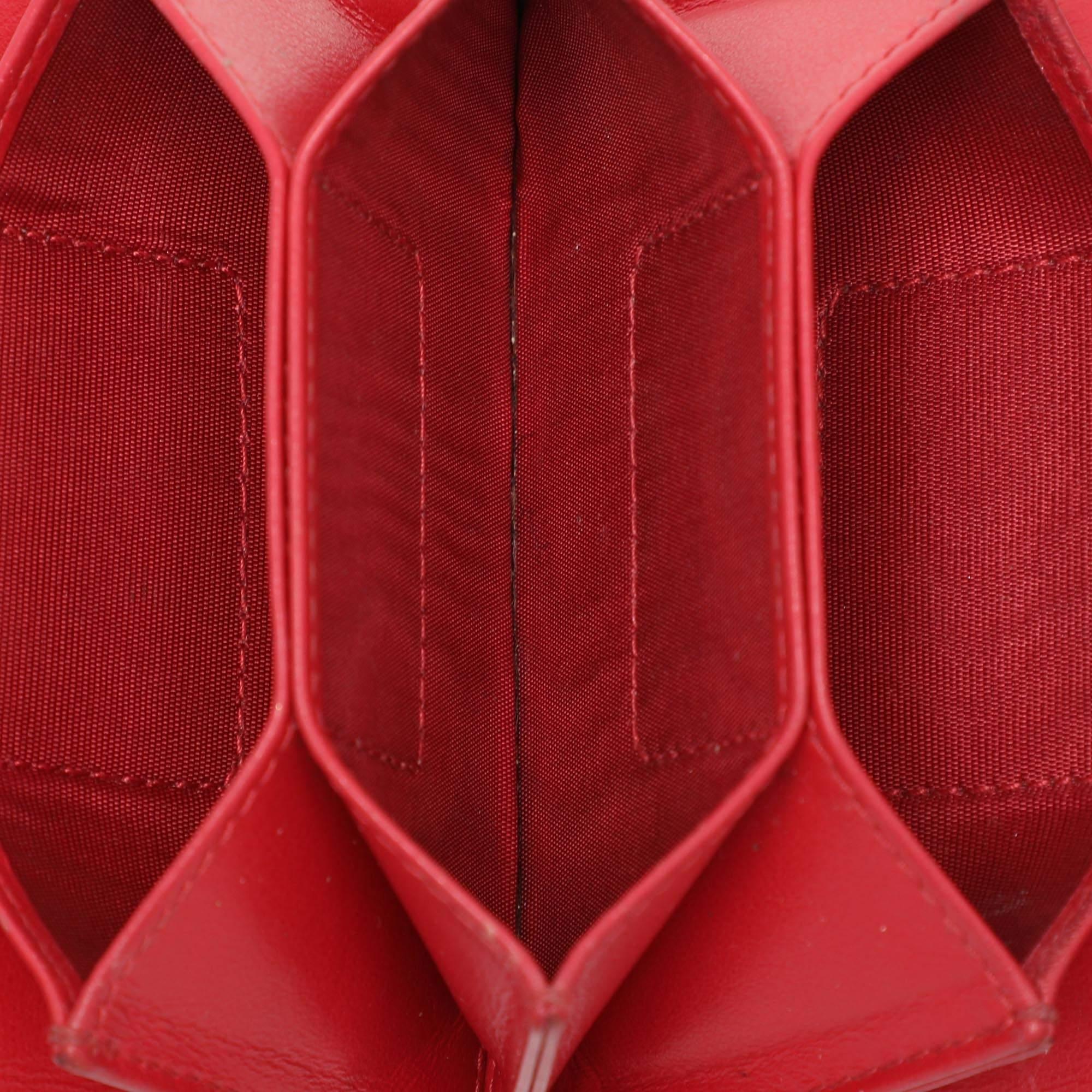 The Lady Dior gusset card case is a Dior creation that is functional durable and high on style This red case has been crafted from patent leather and it carries the signature Cannage pattern. It features a front cross over flap and opens to a nylon