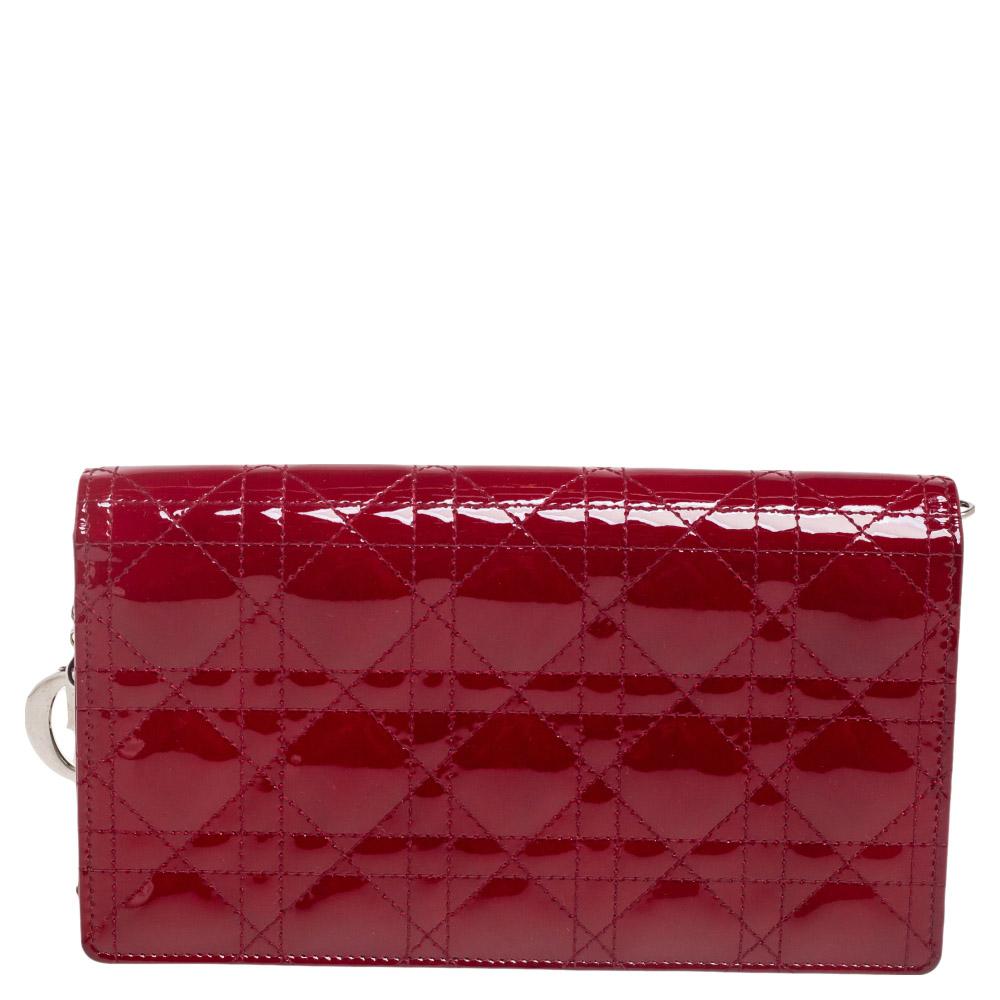 From one of the most emblematic collections by the House of Dior, this flawless Lady Dior wallet on chain certainly needs no introduction. Externally, it is crafted using red Cannage patent leather with a silver-toned chain strap supporting its