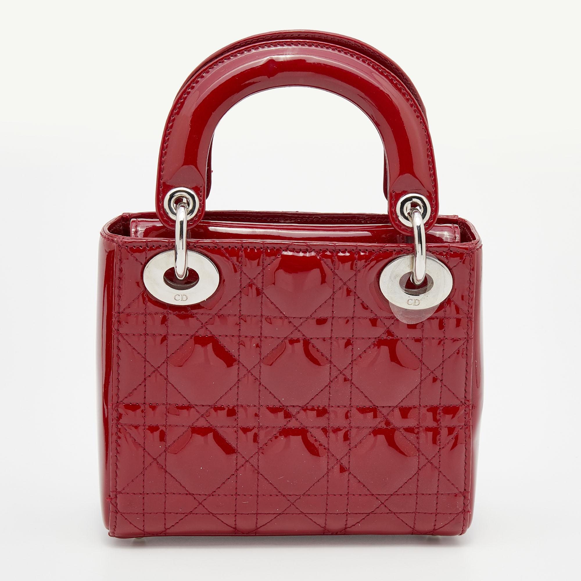 A timeless status and significant design define this impeccable mini Lady Dior tote. An iconic creation of the House, the tote brings eternal poise and elegance to your appearance. It comes crafted in red Cannage patent leather with logo charms