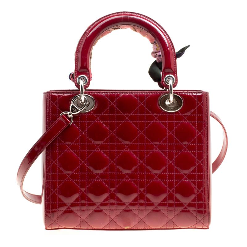 This contemporary Lady Dior tote by Dior will make a charming addition to your outfit. The ravishing red tote is crafted from leather and features the signature cannage pattern. It flaunts dual top handles with a draped scarf, silver-tone DIOR