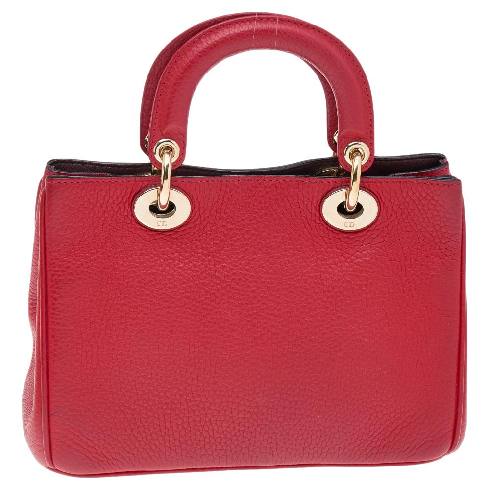 The Diorissimo shopper tote from Dior is a piece that has never gone out of style. The leather bag comes in a red shade with opulent hardware and Dior letter charms. It comes with dual top handles and protective feet at the bottom. A snap button