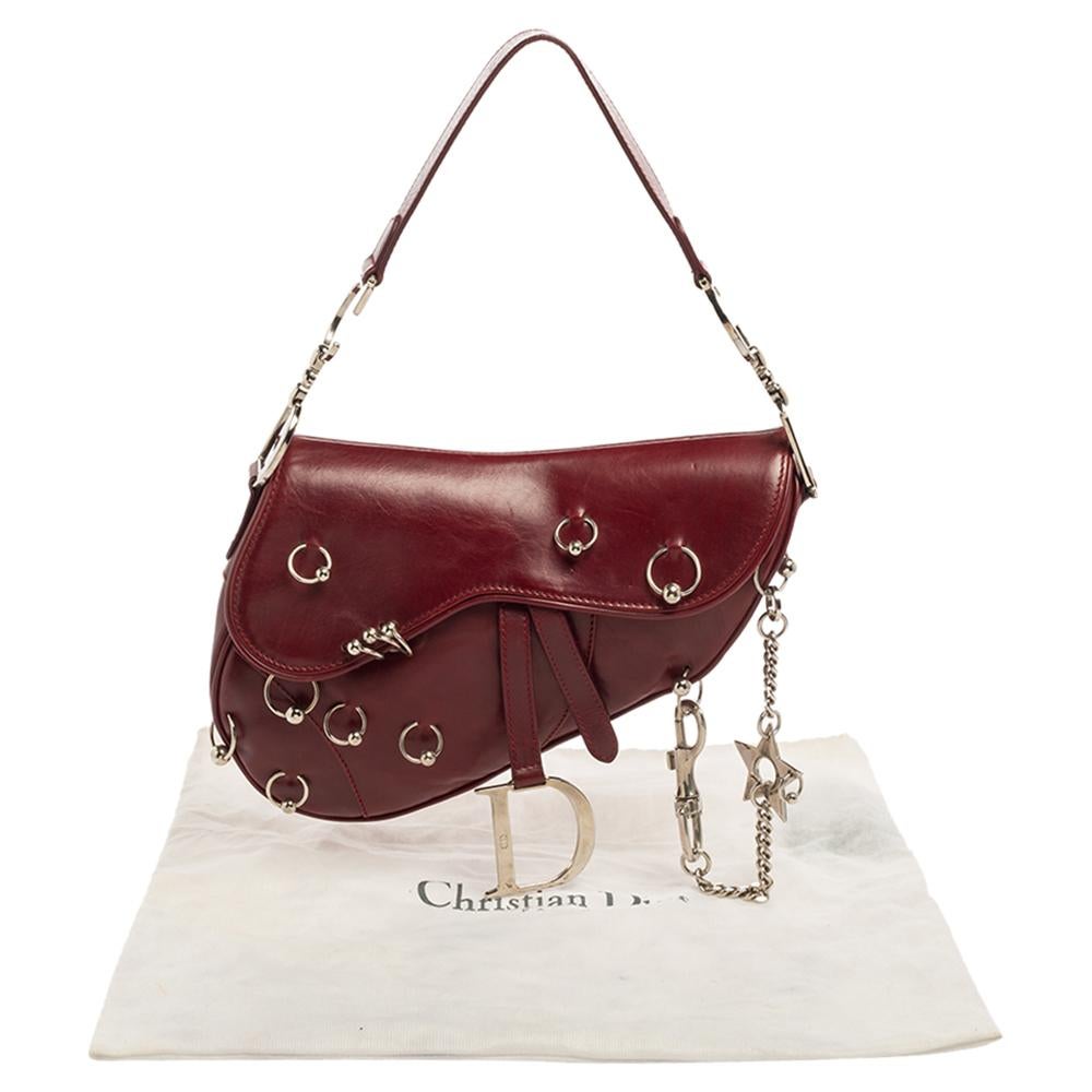 Introduce the Dior Saddle magic to your closet with this rock 'n' roll 'Piercing' version. It is made from leather and decorated with silver-tone hardware accents for a 'piercing' effect. A single handle, logo motifs, and a nylon interior sum the