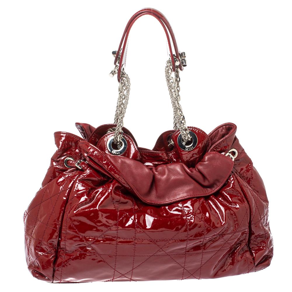 This stylish Le Trente hobo from Dior has been crafted from red patent leather and styled with its signature Cannage pattern. The bag features dual chain straps with leather shoulder rest, a CD cutout charm in silver-tone metal, drawstring closure,