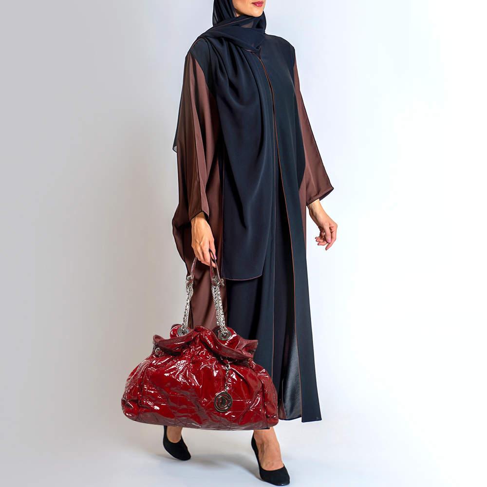 This stylish Le Trente hobo from Dior has been crafted from red patent leather. The bag features dual chain straps with leather shoulder rest a CD cutout charm in silver tone metal a drawstring closure and protective metal feet at the bottom. The