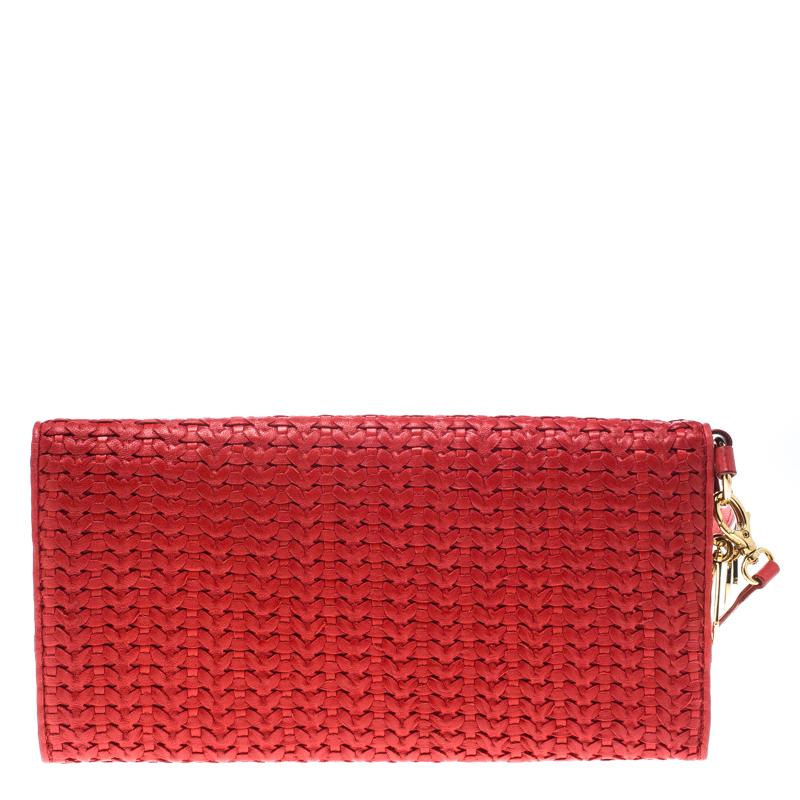 Brimming with elegance and shining with beauty is this beautiful clutch by Dior. It has been crafted from woven leather and designed in a red shade with their signature CD charms in gold-tone dangling on the sides. Complete with fabric-lined