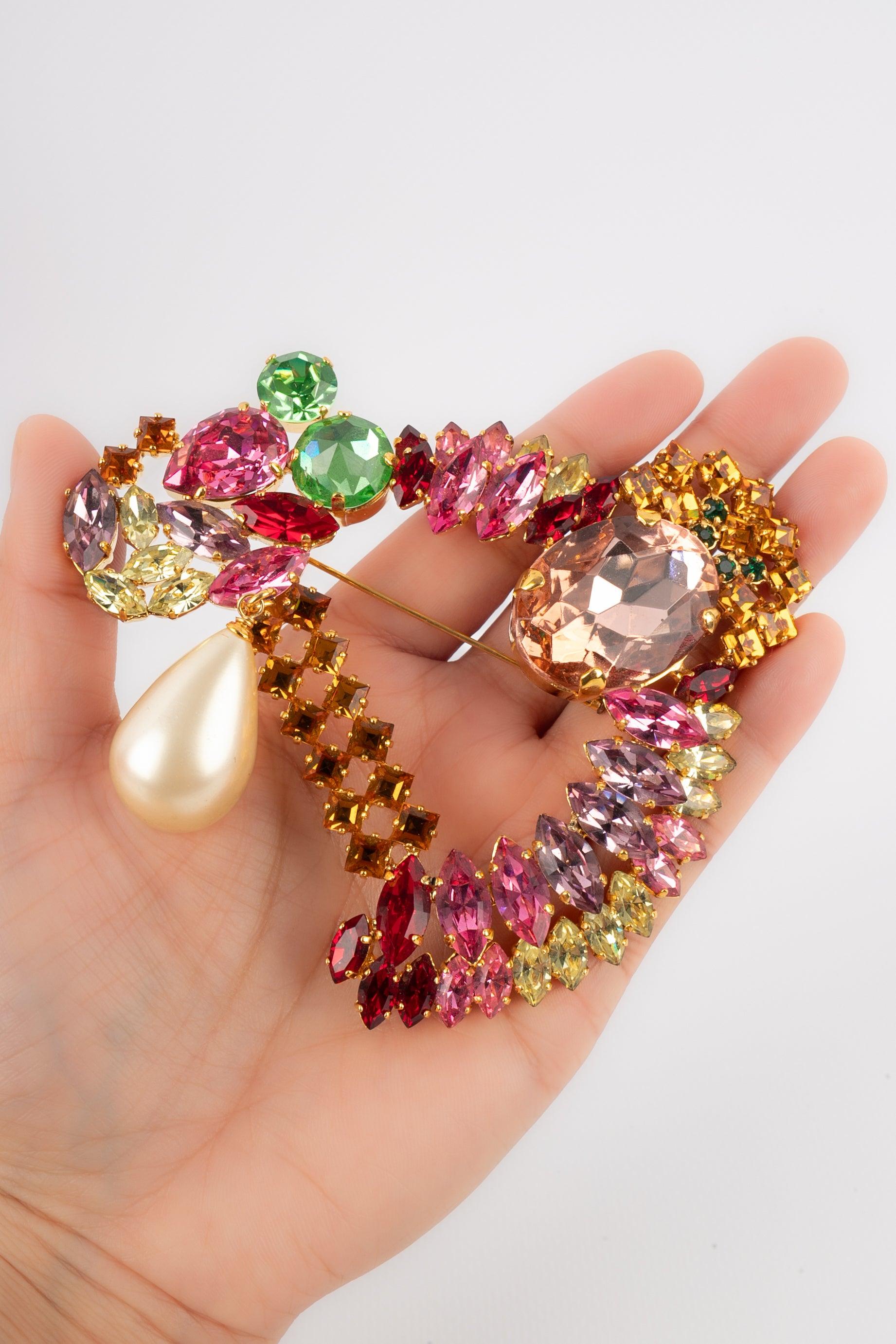 Dior - (Fabriqué en France) Broche en métal doré représentant un D orné de strass de couleur. Broche avec perle fantaisie. Bijoux des années 1990.

Informations complémentaires :
Condit : Très bon état.
Dimensions : 10 cm x 10 cm
Période : 20ème