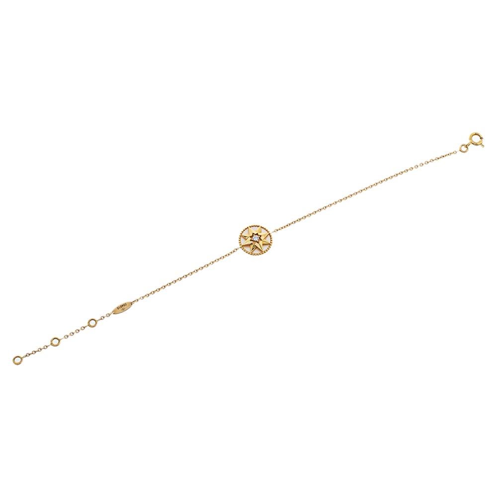 This Rose Des Vents bracelet by Dior exhibits the talisman star as its main highlight. The bracelet's design features a round motif at the centre inlaid with Mother of Pearl and outlined with 18K yellow gold beaded borders. The motif is further