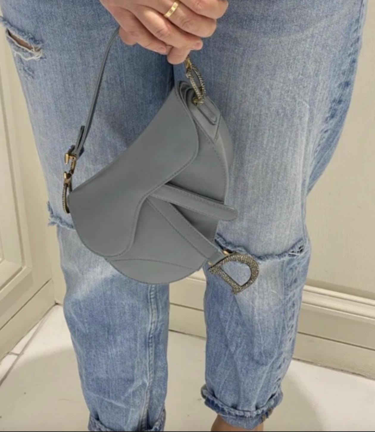 This Dior Saddle Bag is a stunning mini crafted in a luxurious icy grayish blue satin. Cinderella would approve! The bag features the iconic Saddle silhouette with its curved design and distinctive flap that seamlessly blends elegance with modern
