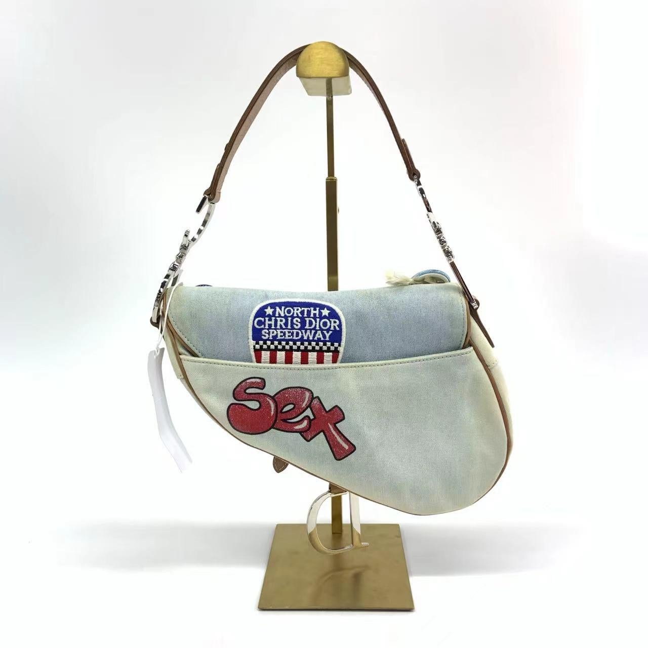 Dior Saddle Bag Vintage Miss Diorella in Blue Denim with Badges, Fall-Winter 2001
These are professional photos of the actual bag.
  This one of a kind vintage piece designed by John Galliano, first seen in Fall-Winter 2001 read-to-wear collection,