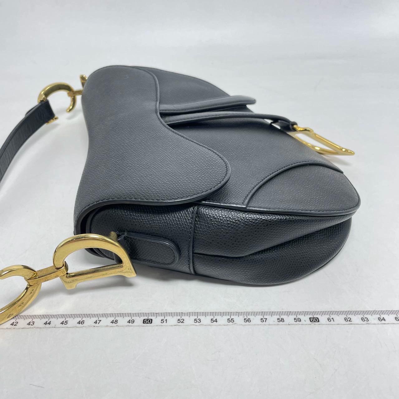 2018 Dior Saddle bag, crafted in black grained calfskin leather, the legendary design comes in size medium, features a magnetic flap, and antique gold-finish CD signature on both sides of the strap. The Saddle bag may be carried by hand worn on the