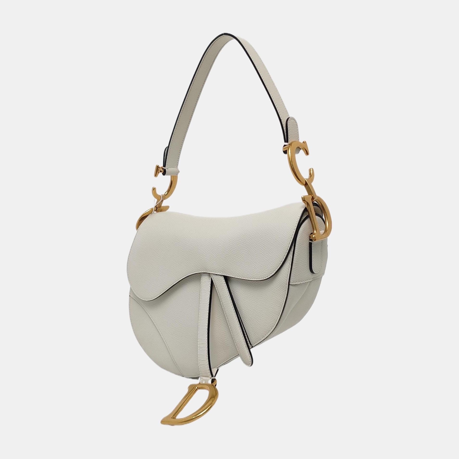 Dior Saddle bag, crafted in white grained calfskin leather, the legendary design comes in size medium, features a magnetic flap, and antique gold-finish CD signature on both sides of the strap. The grained calfskin leather is extremely resistant to