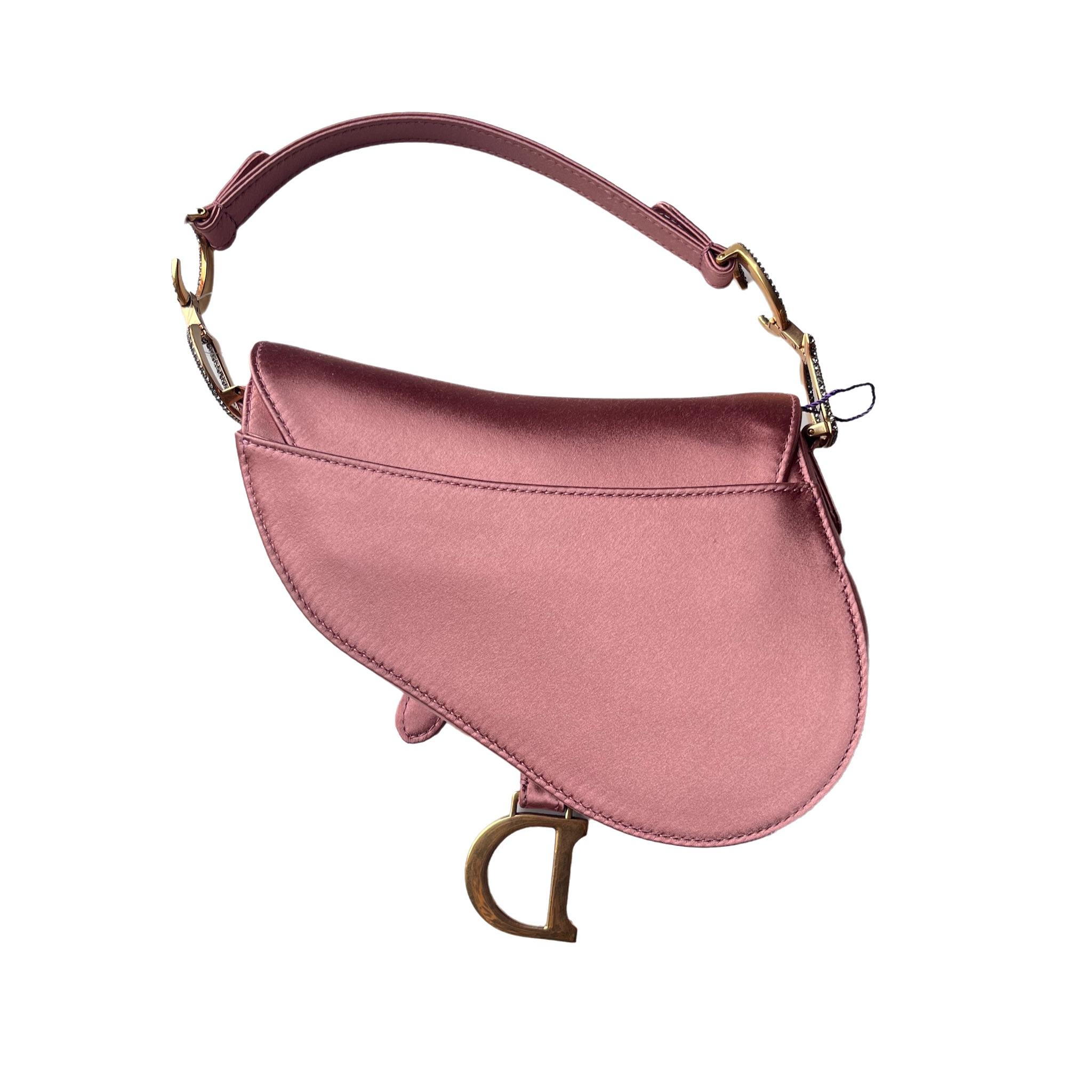 Dior Saddle Bag aus rosafarbenem Seidensatin, das legendäre Design in der Größe Mini, mit magnetischem Überschlag und einem CD-Schriftzug in Kristallverzierung auf beiden Seiten des Riemens. Die Satteltasche kann mit der Hand getragen werden. 

Das