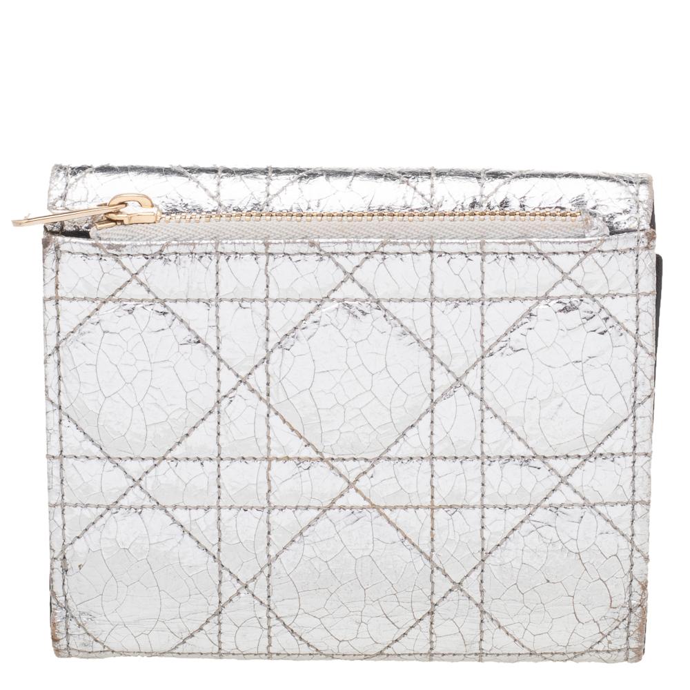 Store your monetary essentials with style and ease in this compact wallet from Dior. This wallet is crafted using silver Cannage foil leather on the exterior with a gold-toned logo-engraved lock closure added to the front. It equips a nylon-lined
