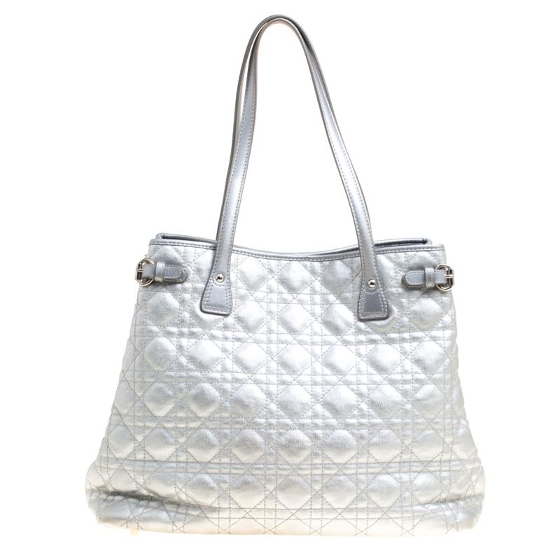 This shopper tote from Dior is a timeless piece. The bag comes in a luxurious canvas cannage exterior with silver-tone hardware and Dior letter charms. It features double top handles and protective feet at the bottom. A buttoned closure opens to a