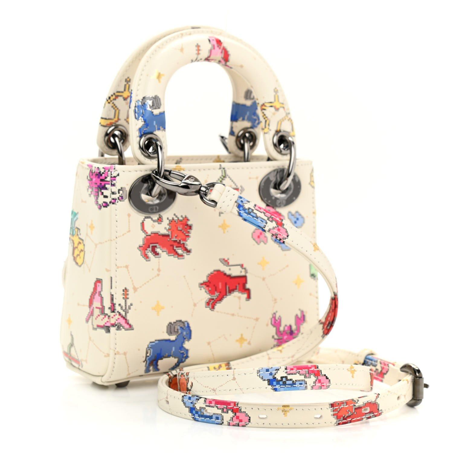 DIOR SMOOTH WHITE CALFSKIN ZODIAC PIXEL PRINTED MICRO LADY DIOR

This Dior bag is constructed of smooth white calfskin leather, featuring a multicolor embroidered art scene on the front. It has smooth white top handles reinforced with dark silver