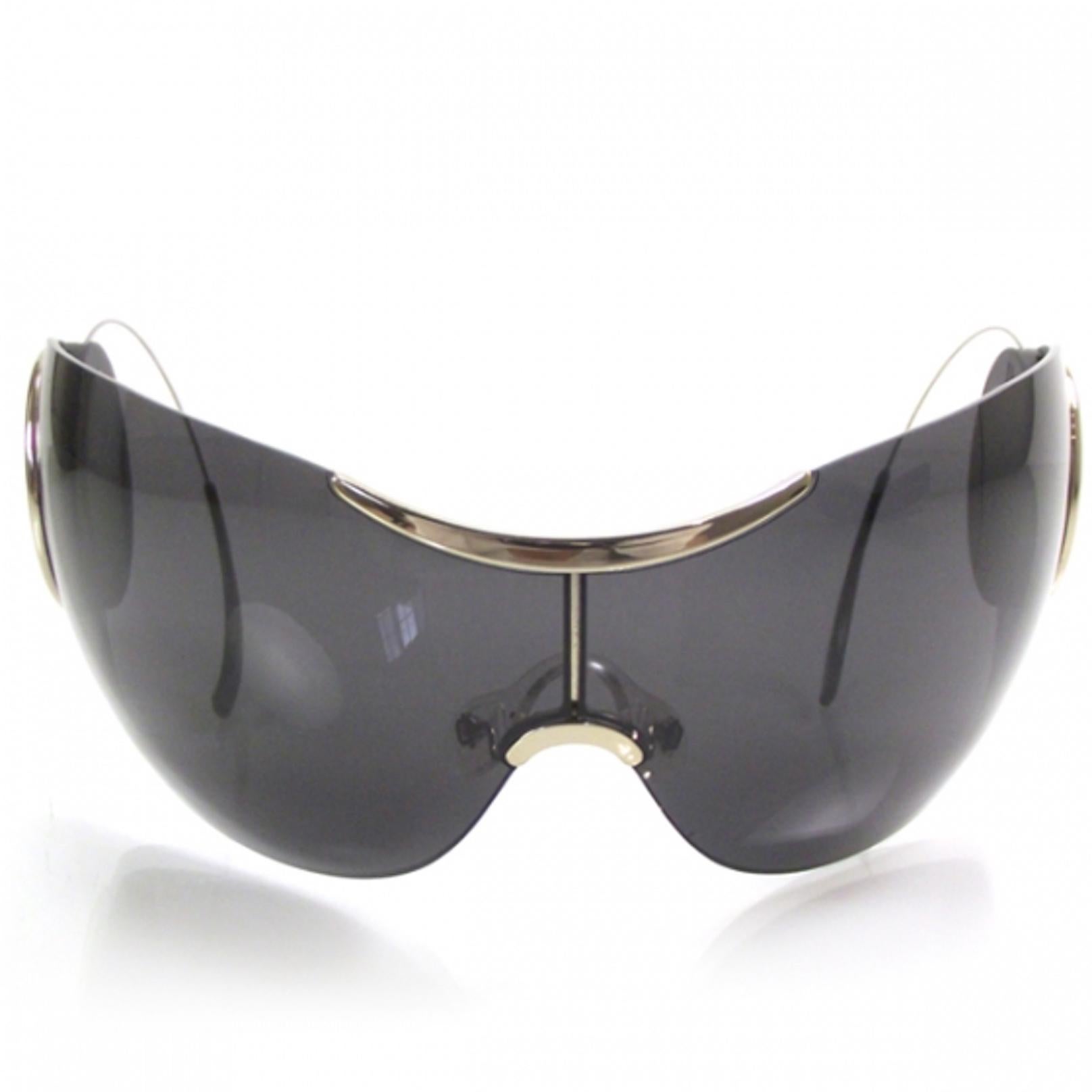 The sunglasses are super stylized and are so sophisticated they appear simple. They have a rimless single piece curved lens of solid gray tint inspired by the classic aviator style but totally new. These also lack a frame for the arms. The rear