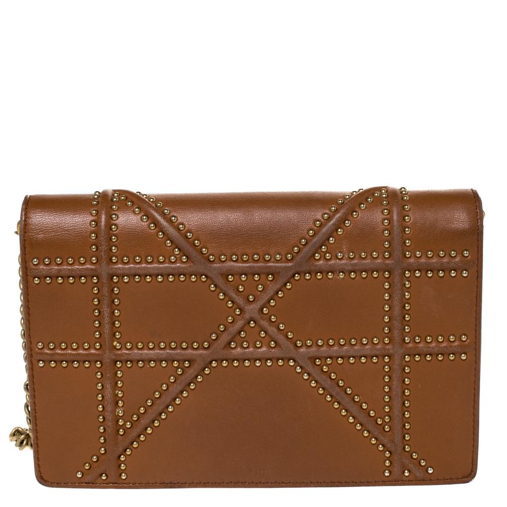 This Diorama has been crafted from tan leather and covered in the brand's signature Cannage pattern. Magnetic closure on the flap, gold-tone studs on the exterior, lined interior, and a shoulder chain is provided for you to carry it. You will surely