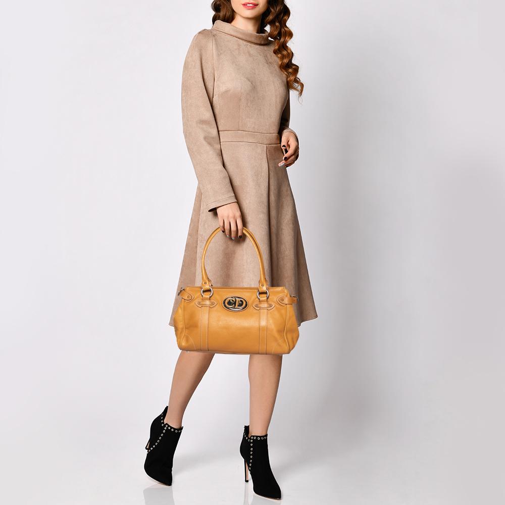 Add a classy finish to your look with this Christian Dior satchel. This satchel is made from smooth tan leather with distinctive contrasting double stitching. The look is finished with a large CD front label, silver hardware, comfortable rolled