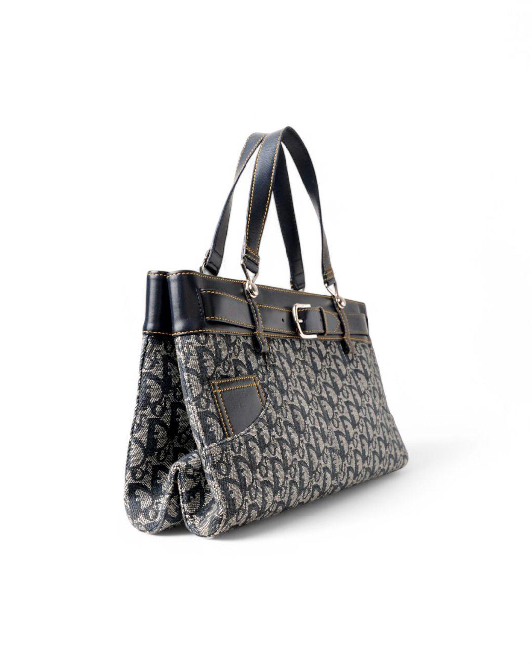 Dior Tote Pocket modèle en denim bleu dans le motif Trotter avec des garnitures en cuir et des ferrures argentées. Il n'est équipé d'aucun fermoir. Doublé intérieurement en nylon ton sur ton avec des poches pratiques, le sac est assez spacieux.