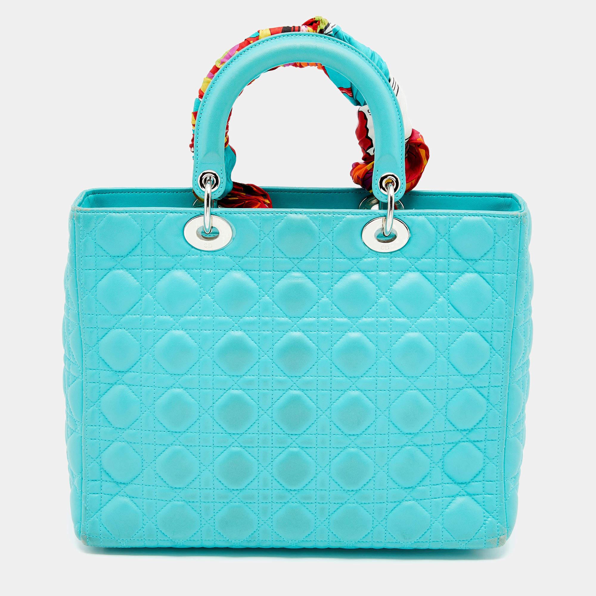 A timeless status and great design mark the Lady Dior tote. It is an iconic bag that people continue to invest in to this day. We have here this large Lady Dior tote crafted from turquoise blue Cannage leather. The bag is complete with two top