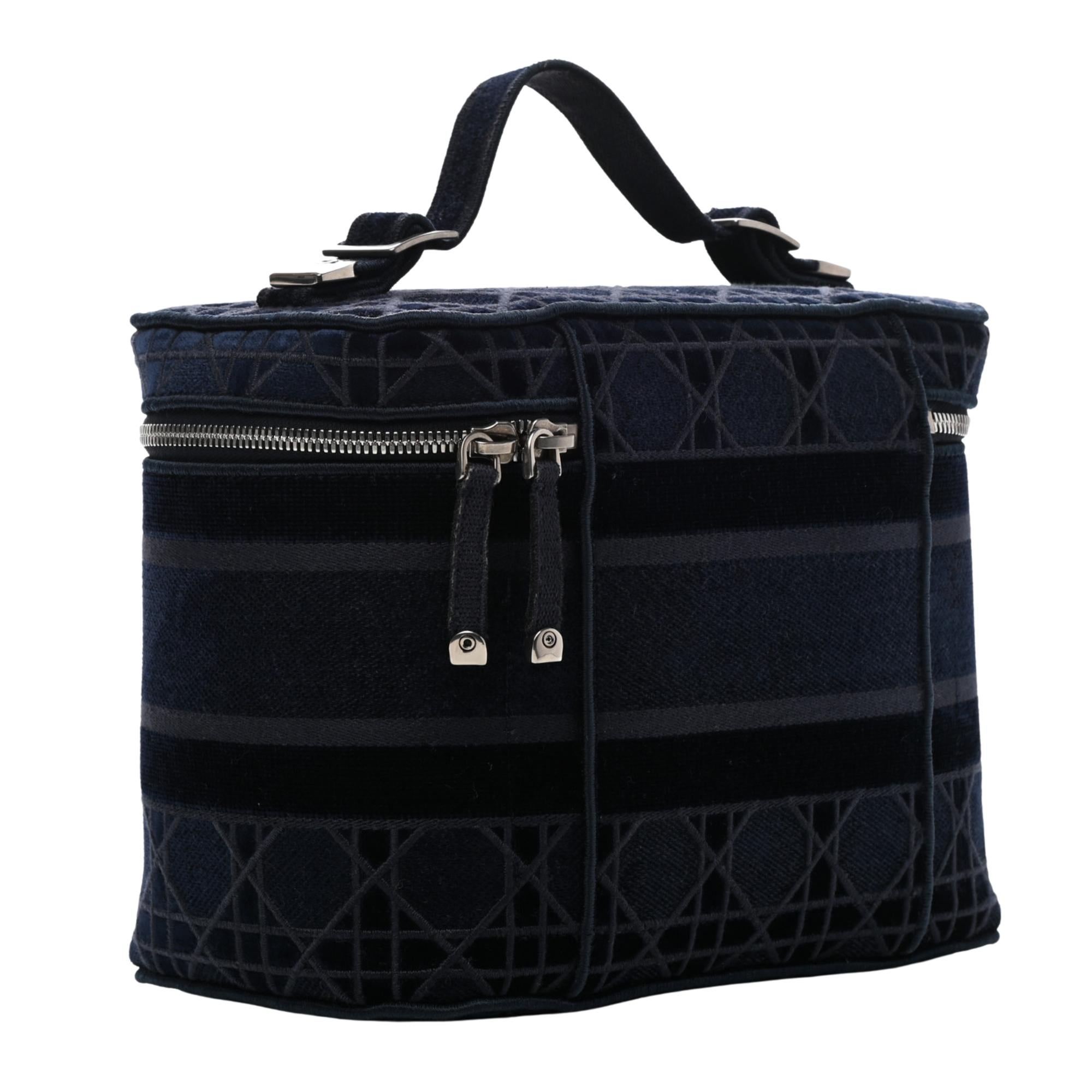 This beauty case is constructed of embroidered navy Cannage canvas with a 'Christian Dior' signature on the front. The bag features a top handle and bold silver hardware. The zipper opens to a matching interior with flat patch pockets.

Color: