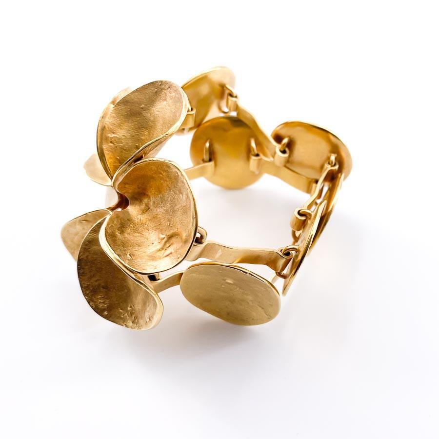 DIOR flower bracelet in gilt metal.

The jewel is signed by Maison DIOR. It is  a double row of metal pieces which ends with the deployment of a flower in metal gilded with fine gold.
In very good condition. We do not notice the presence of shocks