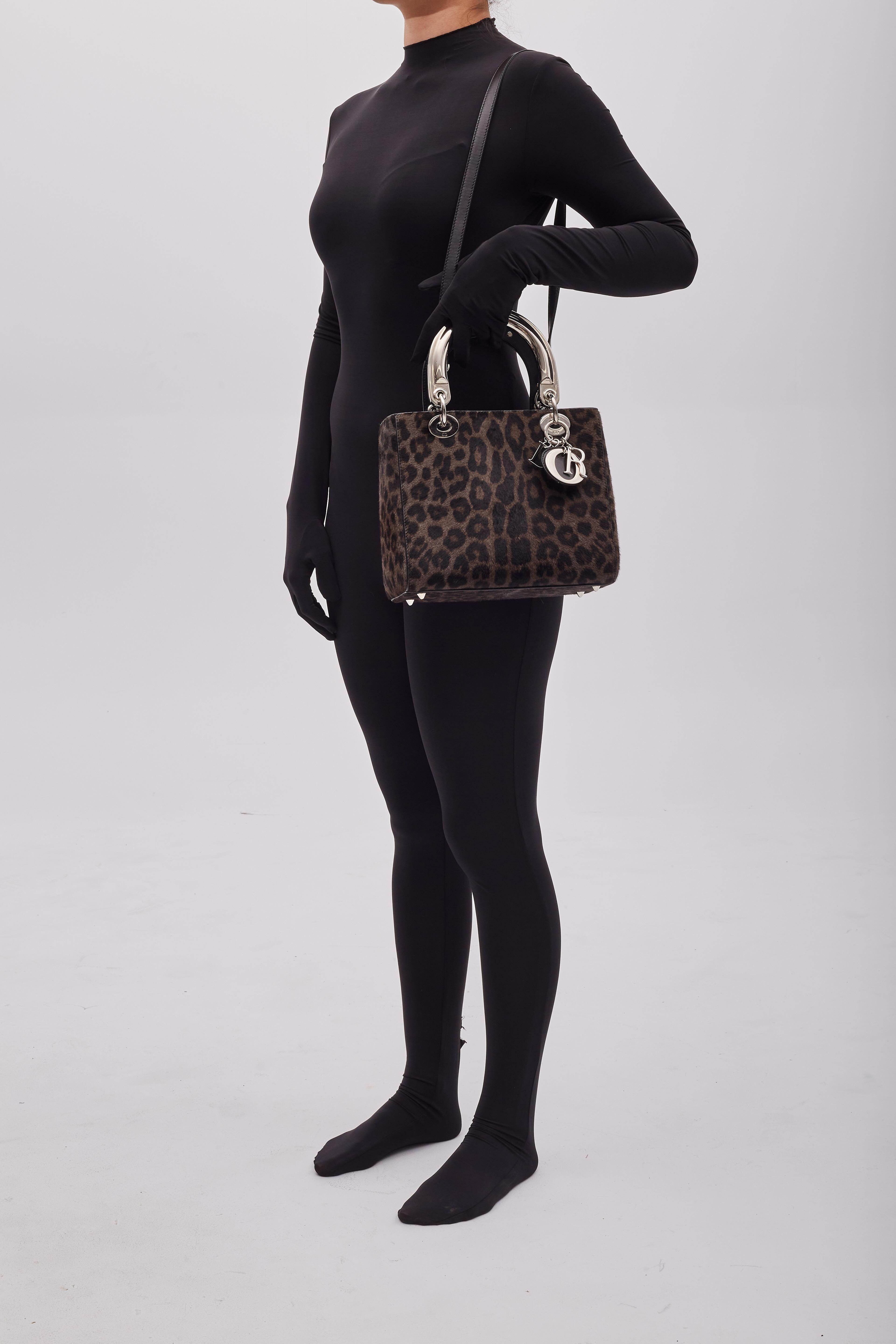 Ce sac Christian Dior est issu de la collection 2013 de Raf Simons. Le sac est en poils de poney marron avec un imprimé léopard, des ferrures argentées, des pieds de protection à la base, deux poignées plates sur le dessus et une bandoulière