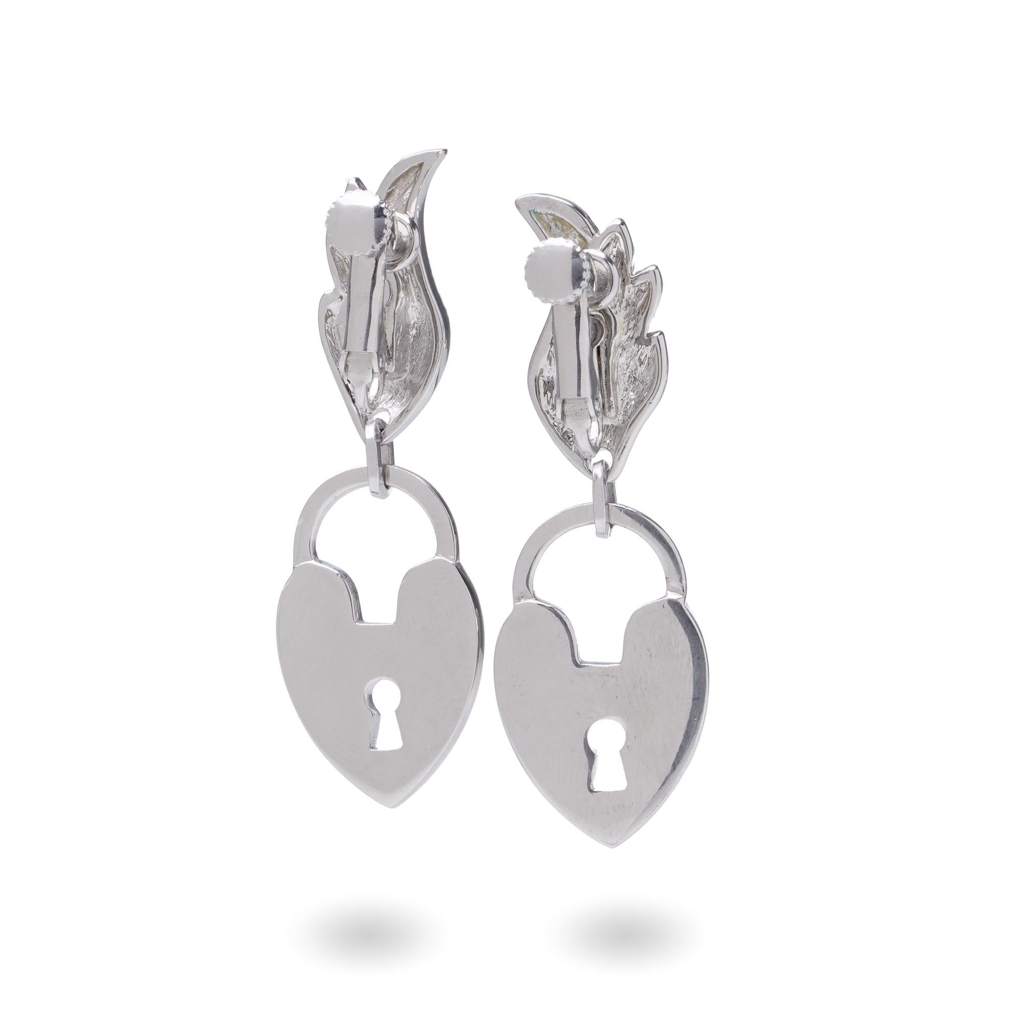 A striking pair of vintage Dior earrings in silver-tone metal, featuring heart-shaped padlock charms engraved with 