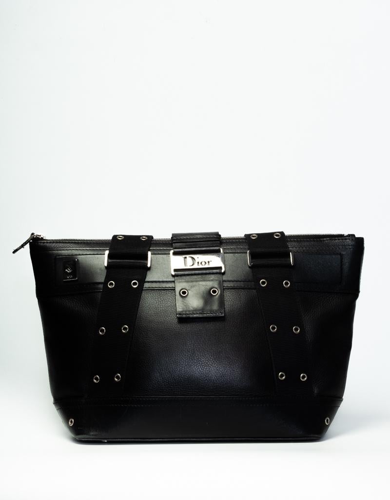 This tote is made with black leather with silver-tone hardware, dual rolled shoulder straps with tonal canvas accents, tonal canvas accents at center featuring grommet embellishments, tonal Diorissimo woven lining, dual pockets at interior walls,