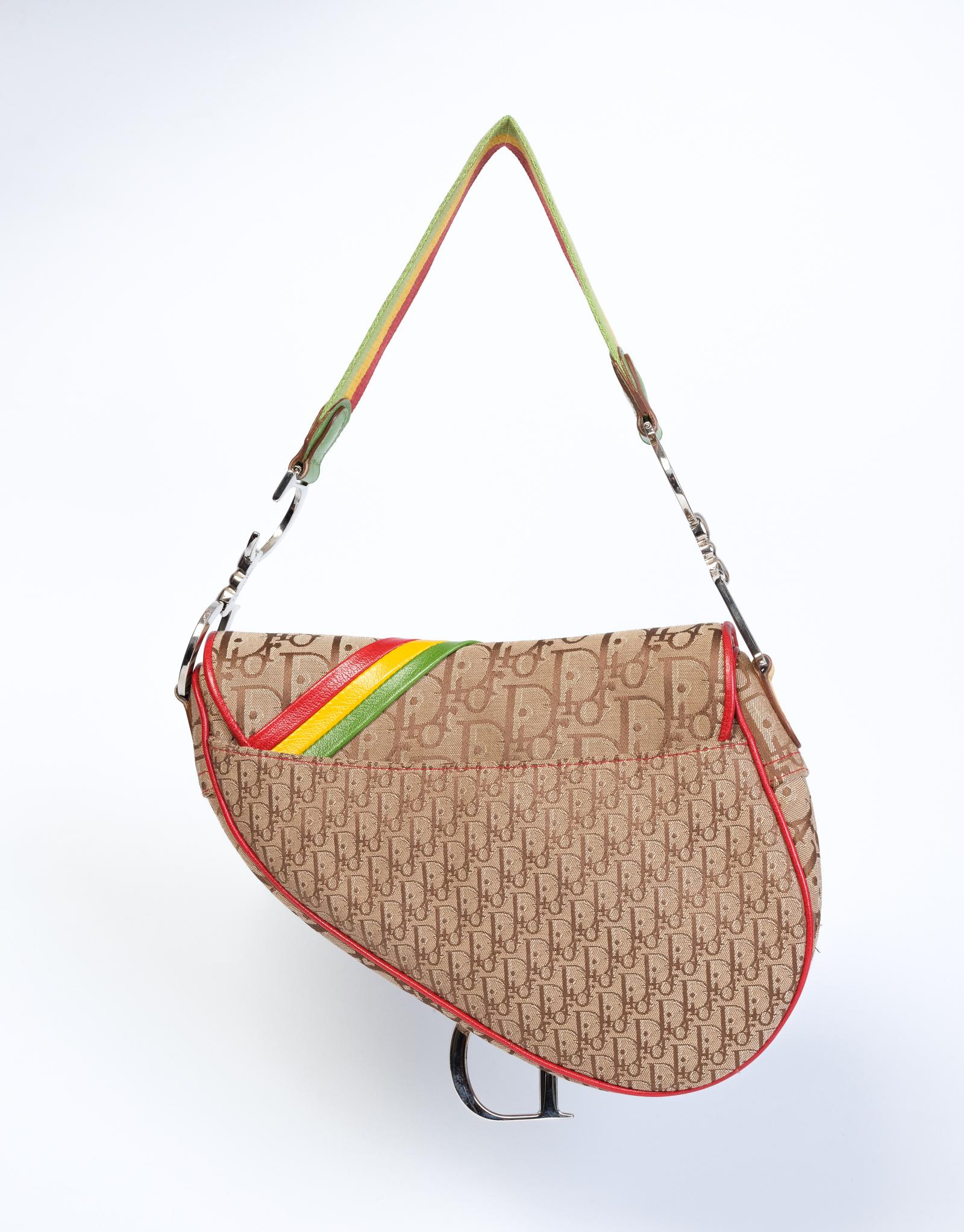 Designed by John Galliano in 2004 this saddle bag has a Jamaican-inspired design for the fall 2004 Rasta collection. The bag is made with canvas with Diorissimo and oblique monogram prints.
The bag features a green, yellow and red leather shoulder