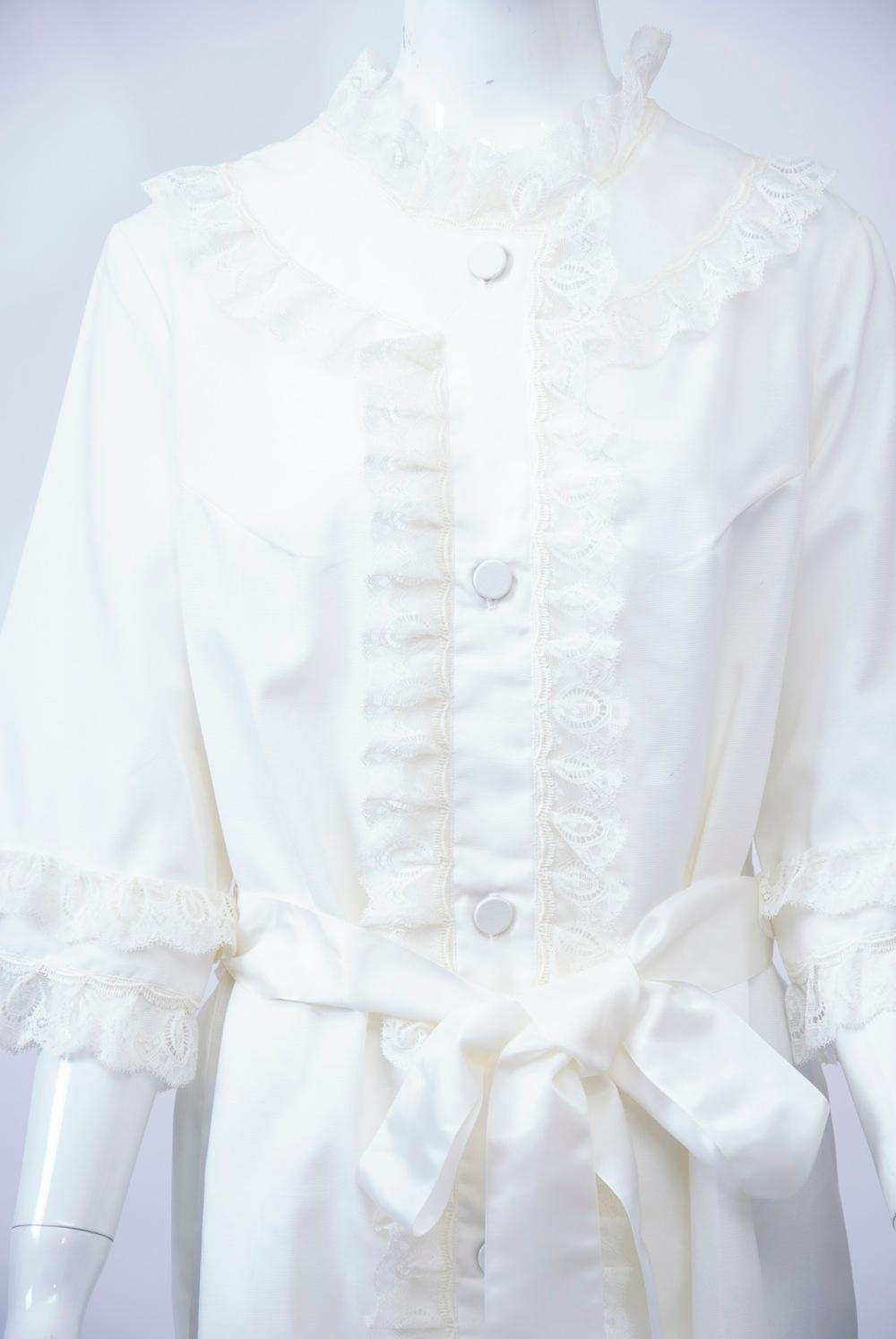 Vintage white lightweight robe by Christian Dior featuring lace trim around all edges and along yoke and button-down placket. The robe also boasts elbow-length sleeves, self buttons down the front, and a satin sash to finish it off. Approximate size