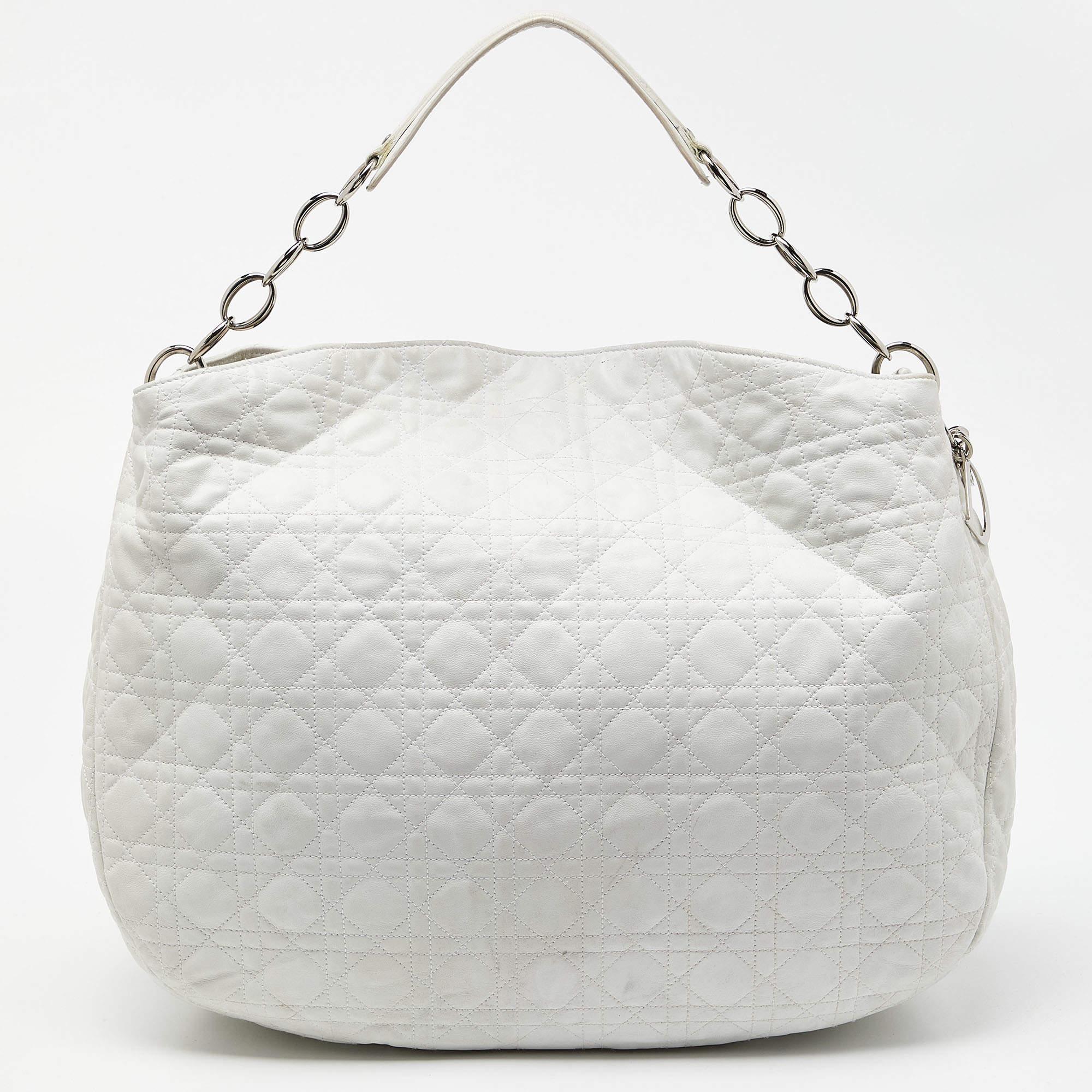 Eine Handtasche sollte nicht nur gut aussehen, sondern auch praktisch sein, so wie diese wunderschöne Hobo von Dior. Diese aus Leder gefertigte Tasche hat ein hübsches, gestepptes Äußeres aus Cannage. Sie hat eine offene Oberseite mit