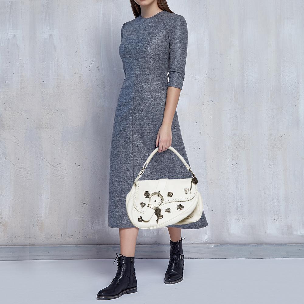 From the house of Dior comes this Double Saddle bag, which is an excellent blend of elegance and style. It comes in white and features a chunky buckle and a key on the front and a well-sized fabric interior. Make an amazing appearance by adorning