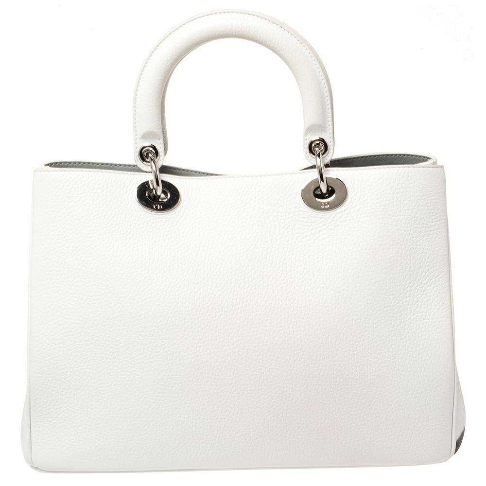 The Diorissimo shopper tote from Dior is a piece that has never gone out of style. The leather bag comes in a pleasing white shade with a 'Secret Garden' print and silver-tone hardware and Dior letter charms. It features two top handles, protective