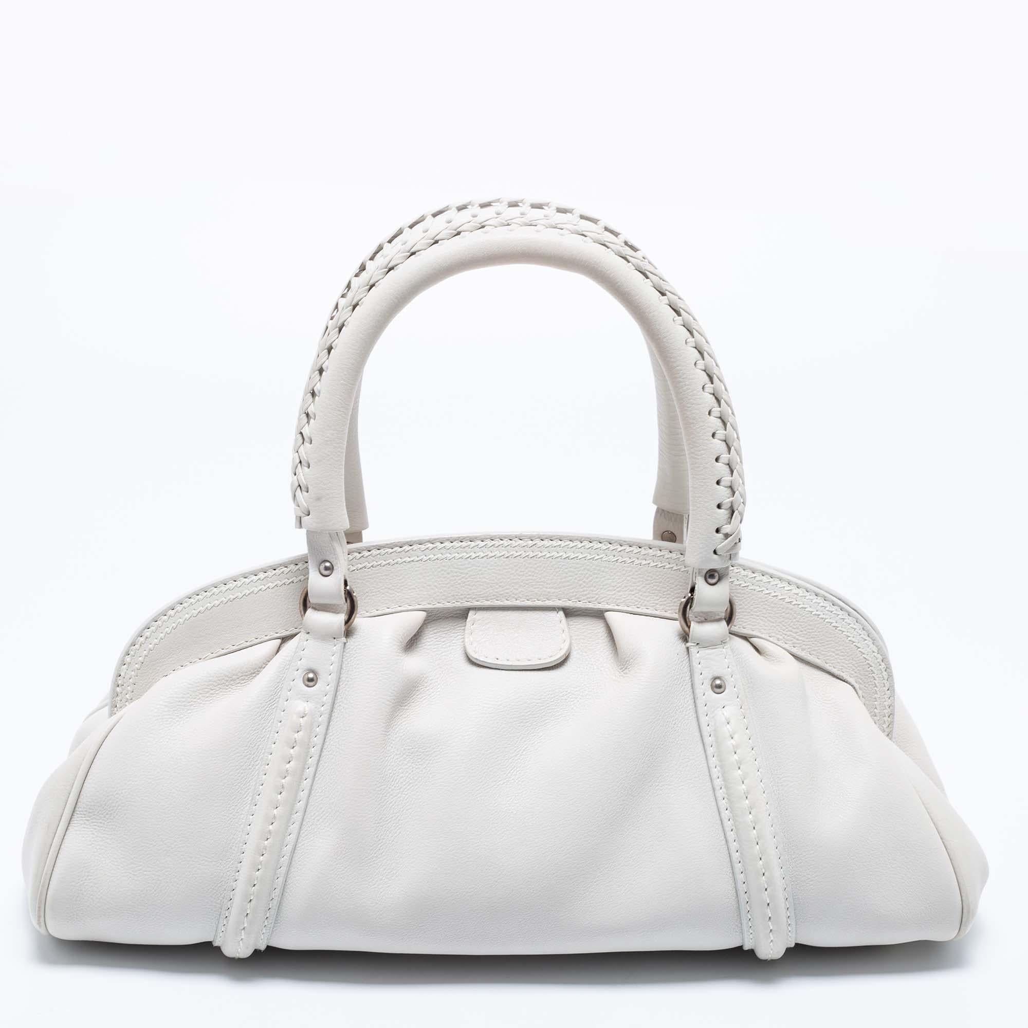 The branded accent at the front lends this Dior satchel a luxe update and high appeal. Crafted from leather, it can be carried conveniently with dual handles at the top, and it is equipped with a roomy lined interior. The frame at the top and the