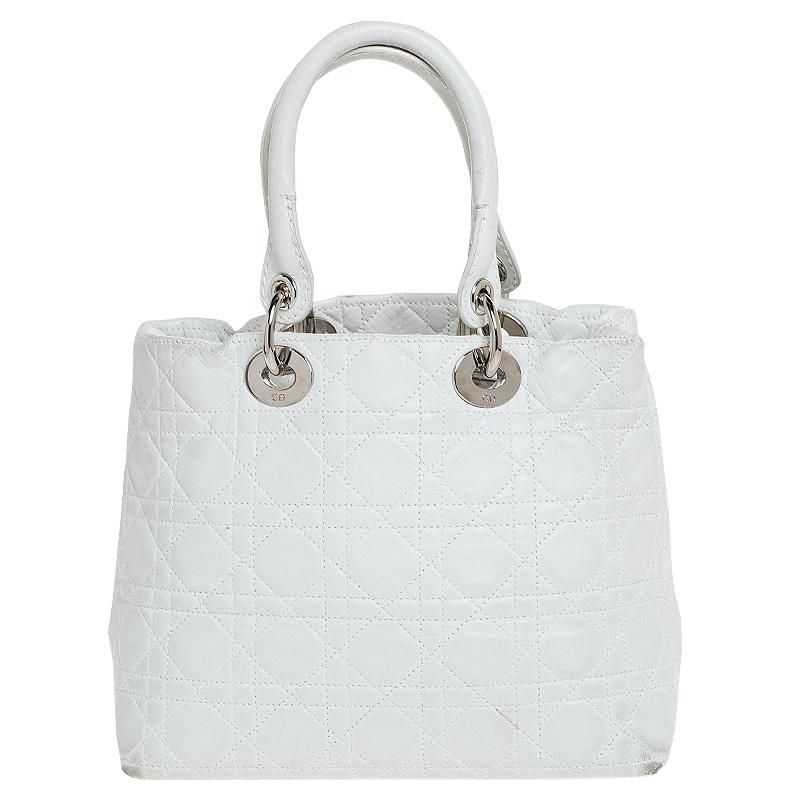 This soft Lady Dior tote from Dior is a timeless piece. The bag comes in a luxurious leather cannage exterior with silver-tone hardware and Dior letter charms. It features double top handles and protective feet at the bottom. The top opens to a