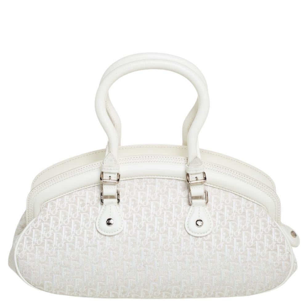 This Detective satchel from Dior is a stylish way of carrying your essentials. Crafted from white leather and Oblique canvas, it has two handles and the brand initials hanging over the front pockets. The zip-top closure opens to a fabric-lined
