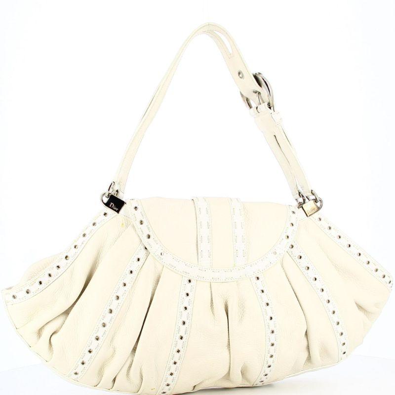 Dior white savane

Very good condition, show some ligth signs of use and wear but nothing visible. A beautiful piece to add in your closet.
Dior white savane in a shell form with white leather topstitching and eyelets.
Leather bag with silver tone