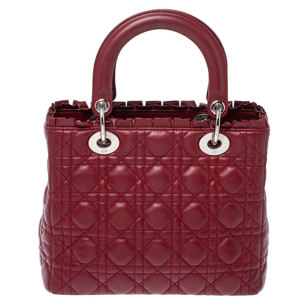 An iconic design when it comes to women's handbags, the Lady Dior is no less than an investment. This red tote has been crafted from leather and it carries the signature Cannage quilt all over and a trim of ruffles on the top. It is equipped with a
