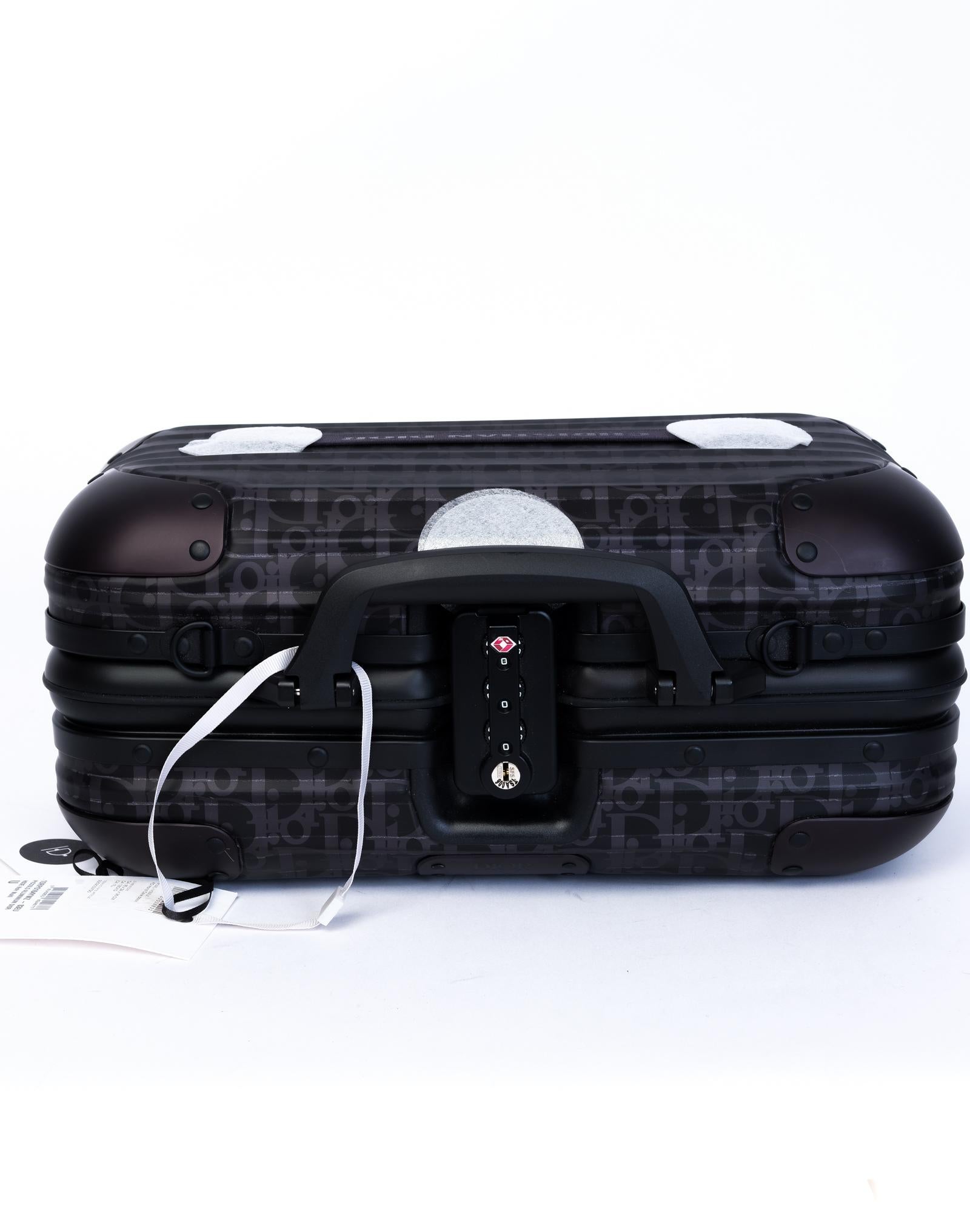 DIOR X RIMOWA Hand Case schwarz schräg Aluminium. Seltene Aluminiumhandtasche mit dem emblematischen Dior Oblique Design auf der Außen- und Innenseite, schwarzen Kunststoffgriffen, einem abnehmbaren schwarzen Nylonriemen, einem Schlüssel- und