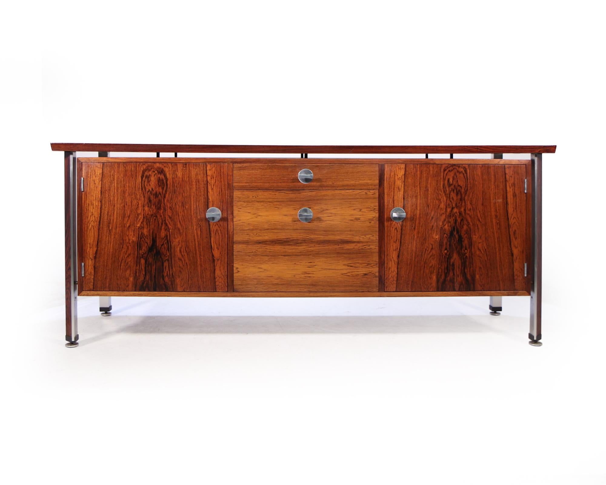 A mid century rosewood sideboard part of the Diplomat range designed by Finn Juhl, produced by France and Son in Denmark in the mid 1960’s , the sideboard has two central drawers and two doors with adjustable shelves behind. The wood inlaid aluminum