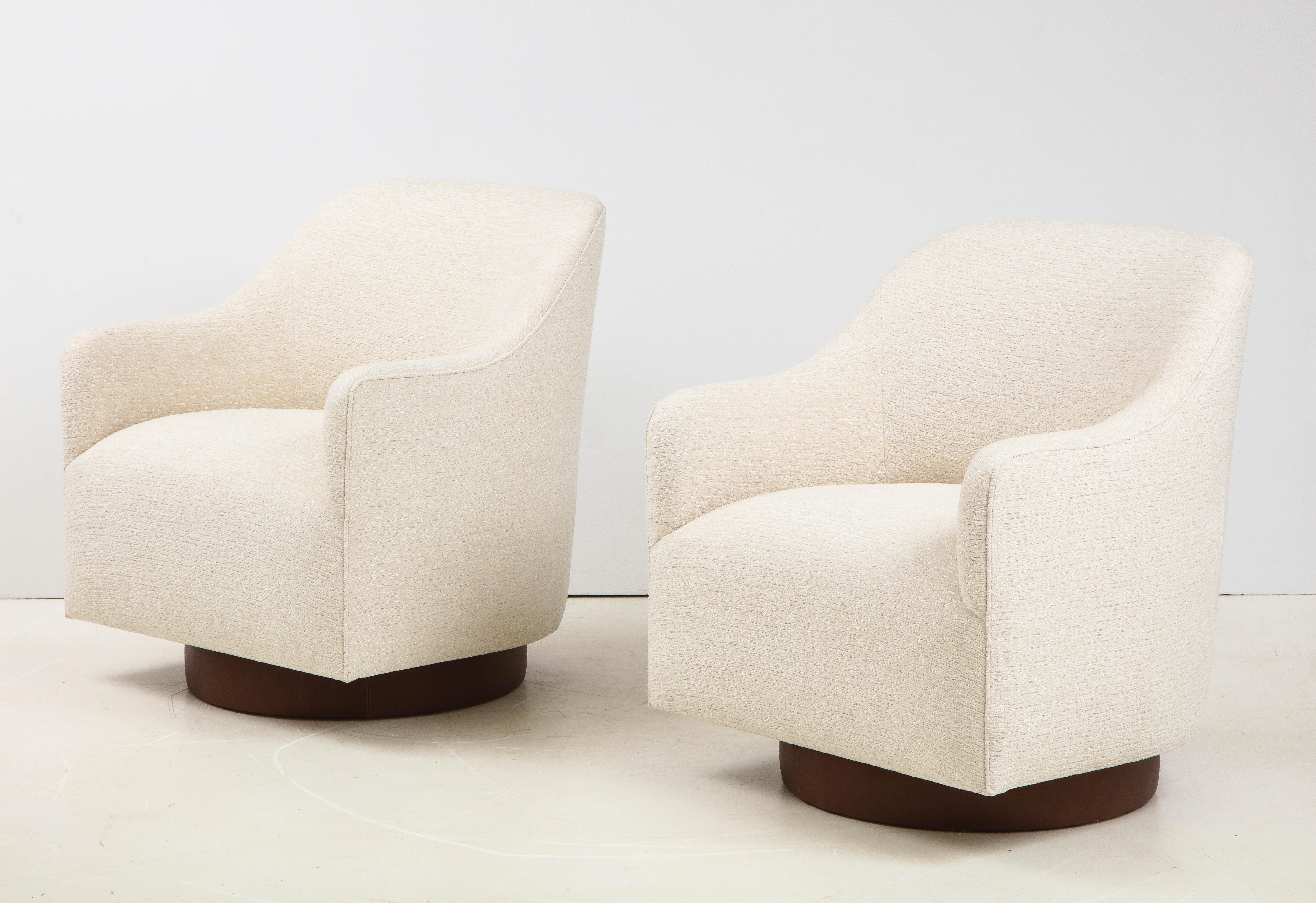 Pair of tilt/swivel club chairs by Milo Baughman for Directional featuring new ivory boucle upholstery and brown leather wrapped base. Chairs are generous in size and have a streamlined sleek profile. New padding, foam.
