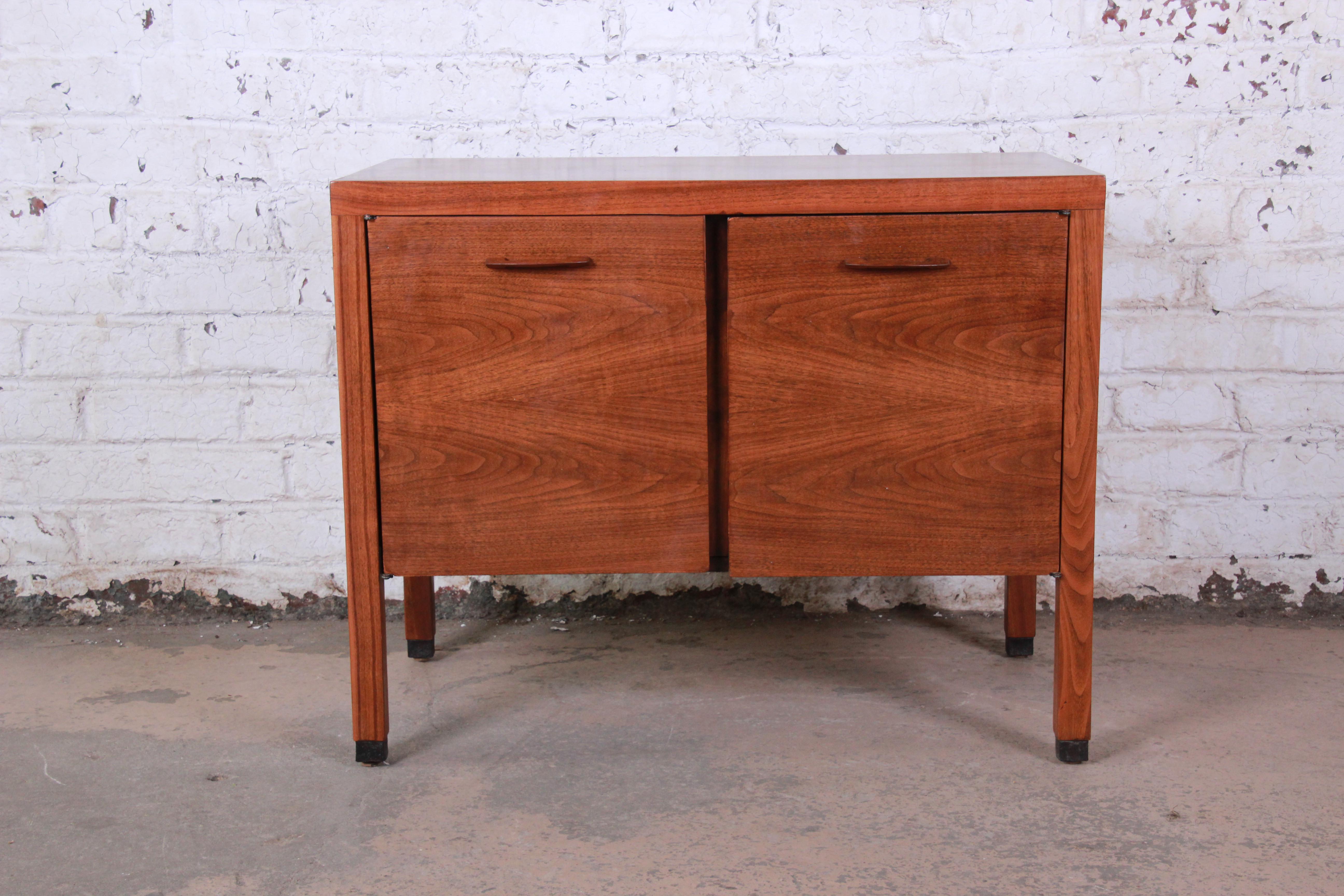 A sleek Mid-Century Modern walnut small credenza or record cabinet by Directional. The credenza features gorgeous walnut wood grain and Minimalist midcentury Danish-inspired design. It offers good storage, with two adjustable shelves behind two