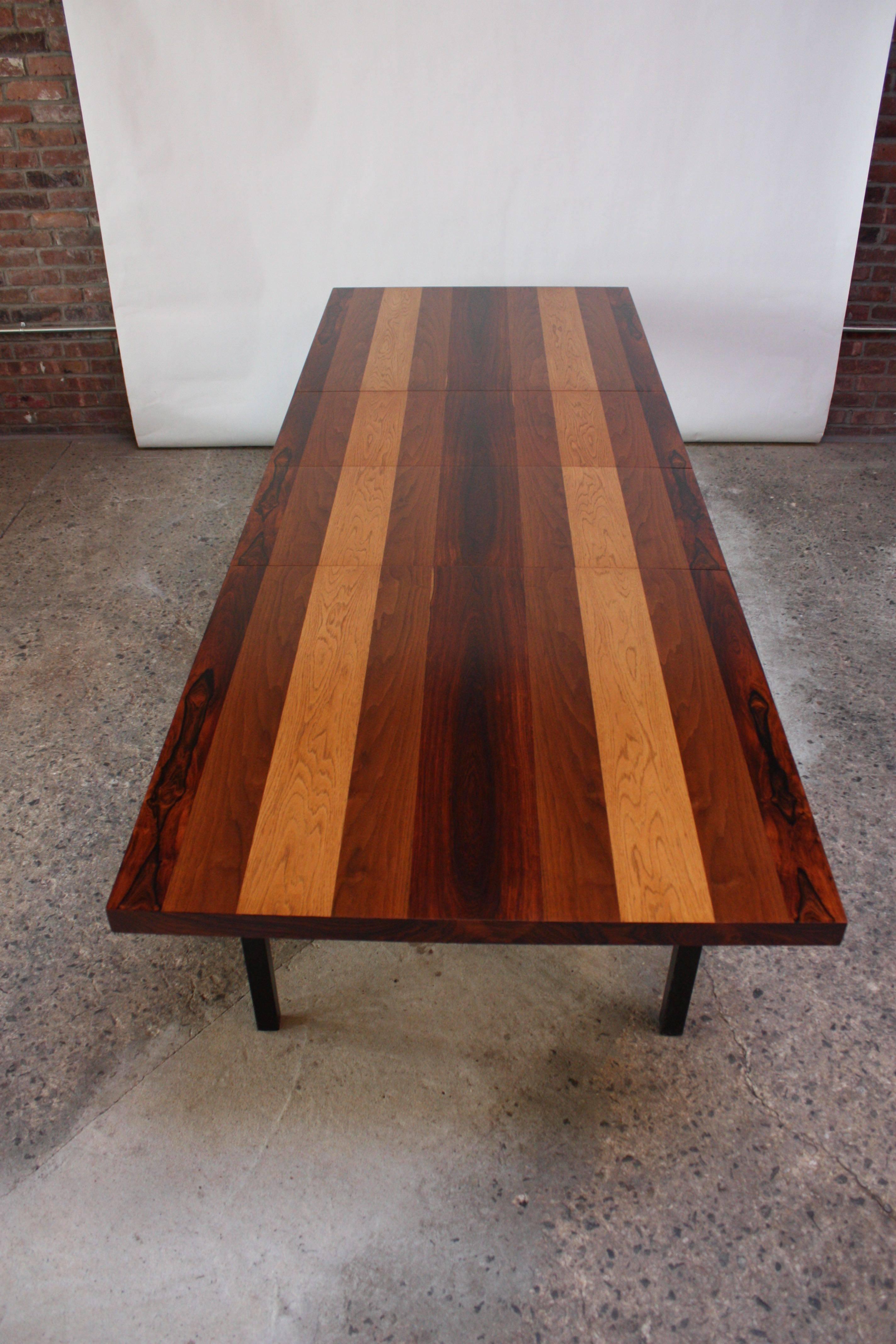This Milo Baughman dining table was designed for Directional in the early 1960s and is composed of walnut, rosewood and English brown oak banding (original black lacquer on legs and apron is intact and is a matte finish, not polished or glossy). The