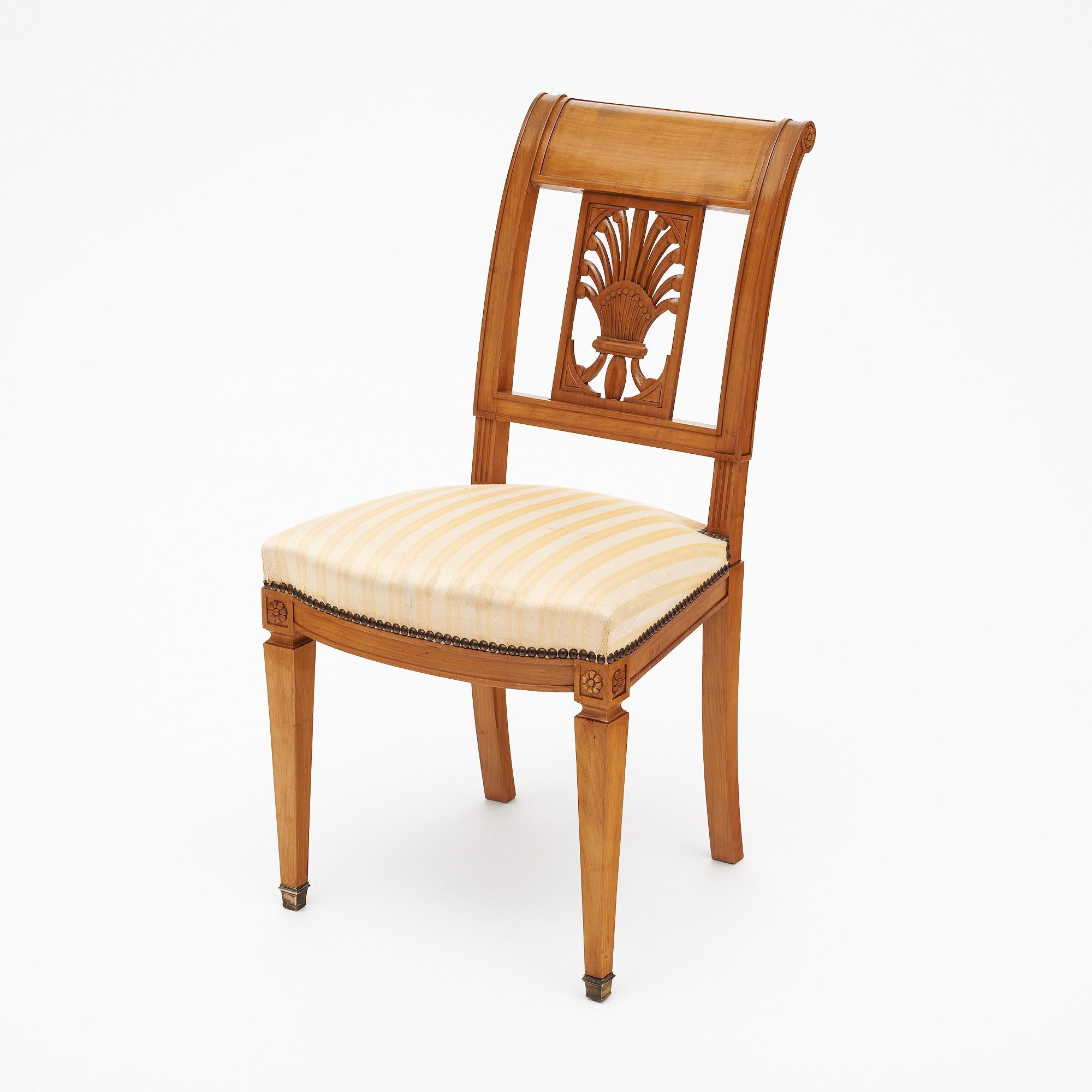Directoire style antique French chairs made with solid wood construction that has been finished with a lustrous French polish of museum quality. We love the elegant stylized acanthus leaf details on the back of the chairs and the tapered front legs